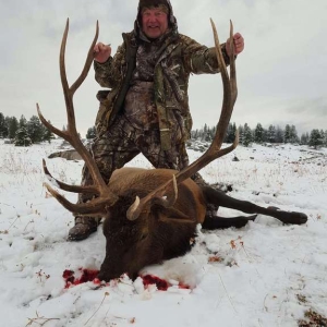 Hunter posing in the snow with his bull elk